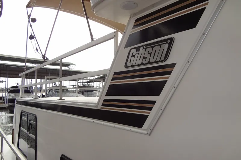 Slide: The Image of 2005 Gibson 44 boat with distinctive logo and sleek design at marina. - 7