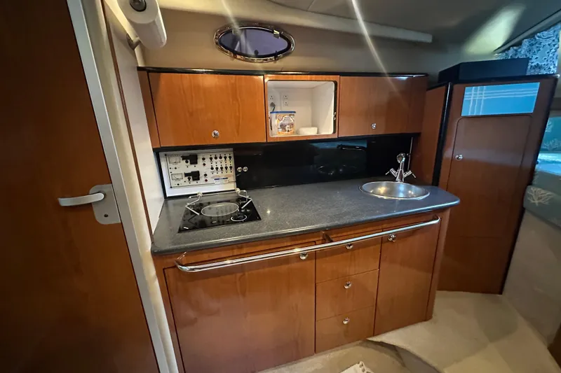Slide: The Image of 2000 Chaparral Signature 300 boat interior kitchen with stove, sink, and wooden cabinetry. - 20
