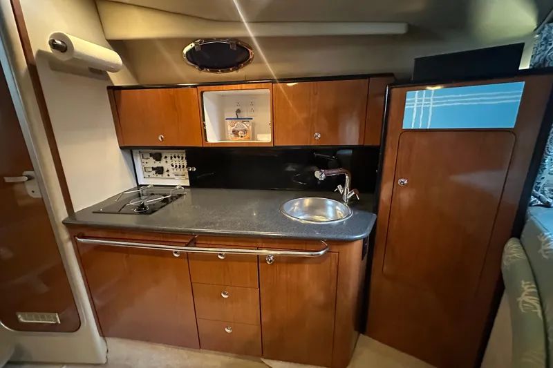 Slide: The Image of 2000 Chaparral Signature 300 boat interior with kitchenette, featuring wood cabinets and a compact sink. - 21