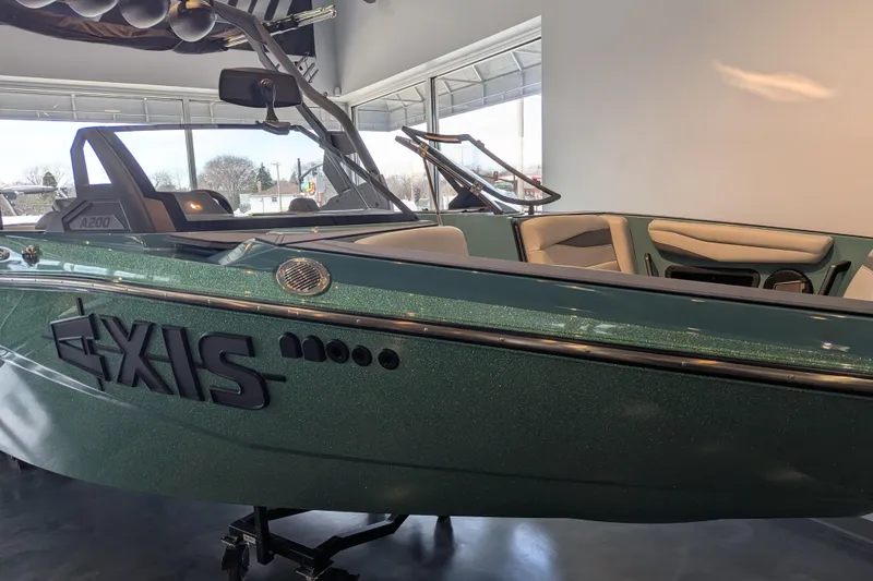 Slide: The Image of 2026 Axis A200 boat in showroom, green exterior, sleek design. - 2