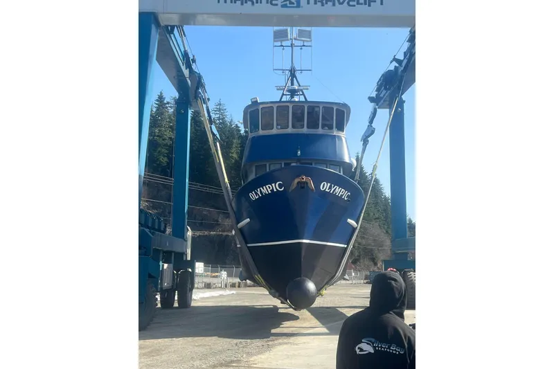 Slide: The Image of Blue 1976 Custom 54 Steel Fishing Vessel "Olympic" in dry dock, surrounded by trees. - 11