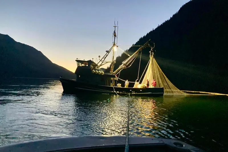 Slide: The Image of Custom 54 Steel Fishing Vessel, 1976, illuminated at dusk on calm waters. - 6