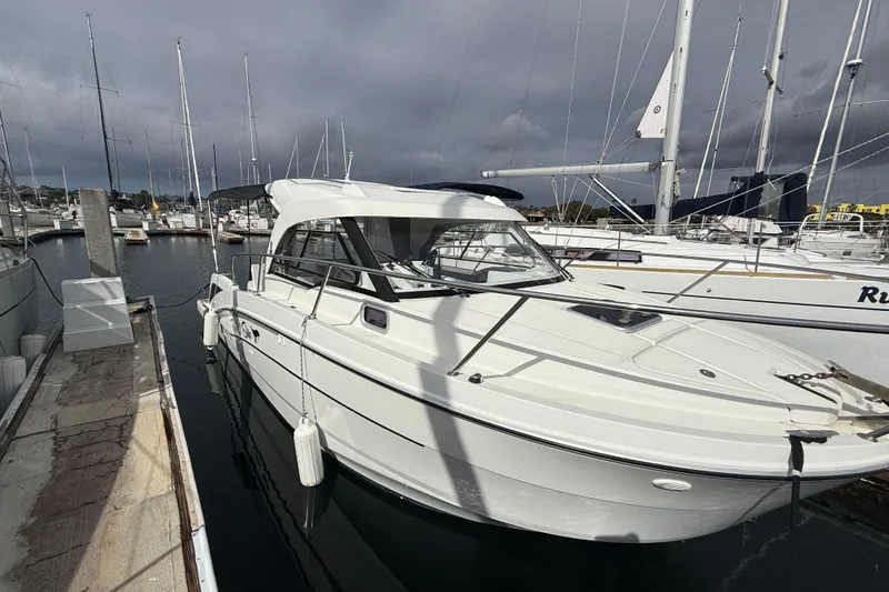 Slide: The Image of 2021 Beneteau Antares 8 docked at a marina under cloudy skies. - 2