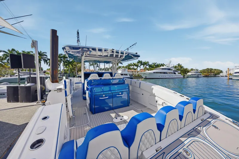Slide: The Image of 2019 Midnight Express 43 Open boat with blue seating, docked by palm trees and yachts. - 13
