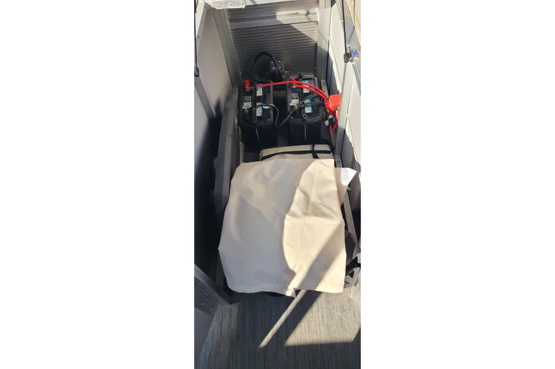 Slide: The Image of 2023 Bennington L23 boat battery compartment with wiring and cover. - 16