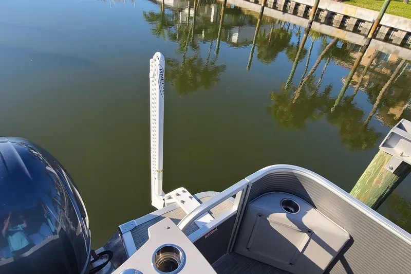 Slide: The Image of 2023 Bennington L23 boat docked on calm water with palm tree reflections. - 21