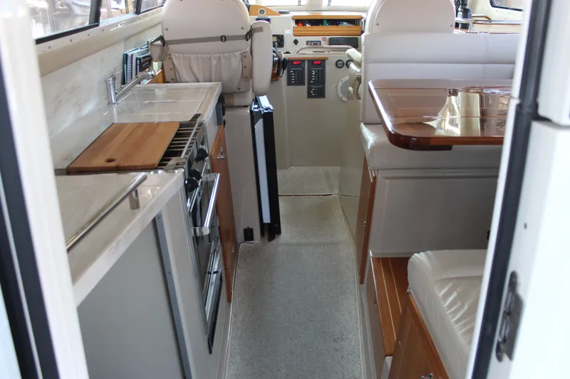 Slide: The Image of Interior of a 2016 Aspen B100 boat featuring a compact kitchen and seating area. - 14