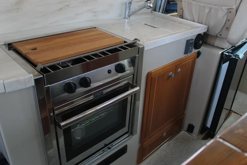 Slide: The Image of Compact kitchen in 2016 Aspen B100 with stove, sink, and wooden cabinetry. - 17
