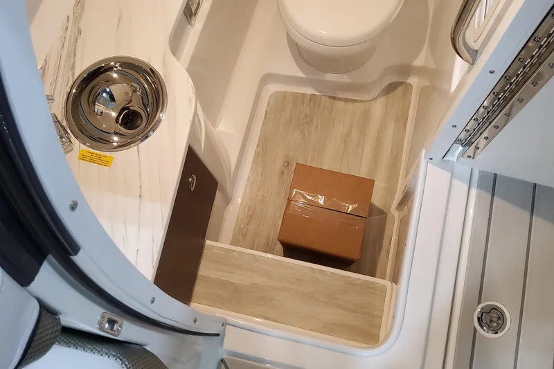 Slide: The Image of 2026 Formula 310 Bowrider OB interior with sink, toilet, and a cardboard box on the floor. - 60