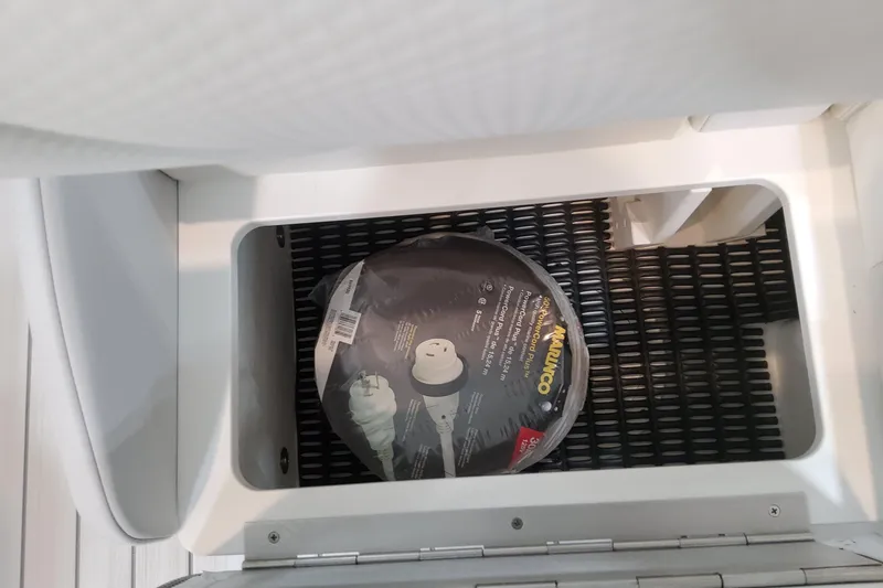 Slide: The Image of Storage compartment in 2026 Formula 310 Bowrider OB boat with coiled power cord. - 84