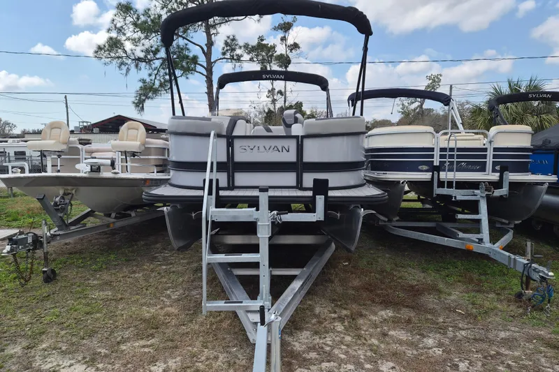 The Image of 2024 Sylvan L3 CLZ DH pontoon boat on trailer, surrounded by other boats. - 1