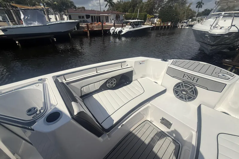 Slide: The Image of 2024 Yamaha Boats 255 FSH Sport H interior with seating and speaker, docked by waterfront. - 9