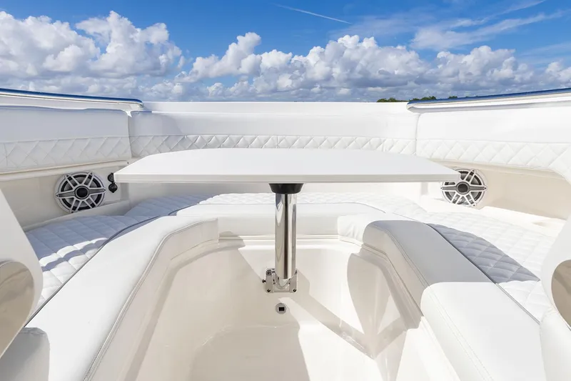 Slide: The Image of Manufacturer Provided Image: 2025 Pursuit DC 306 Dual Console boat interior with white seating and table under blue sky. - 7