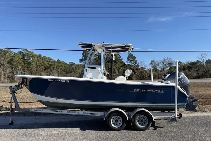 The Image of 2011 Sea Hunt Triton 225 boat on trailer, parked roadside under clear sky. - 1