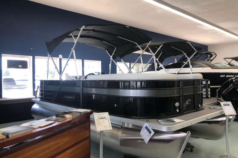 The Image of 2021 Crest Classic LX 200 L pontoon boat displayed indoors with canopy. - 0