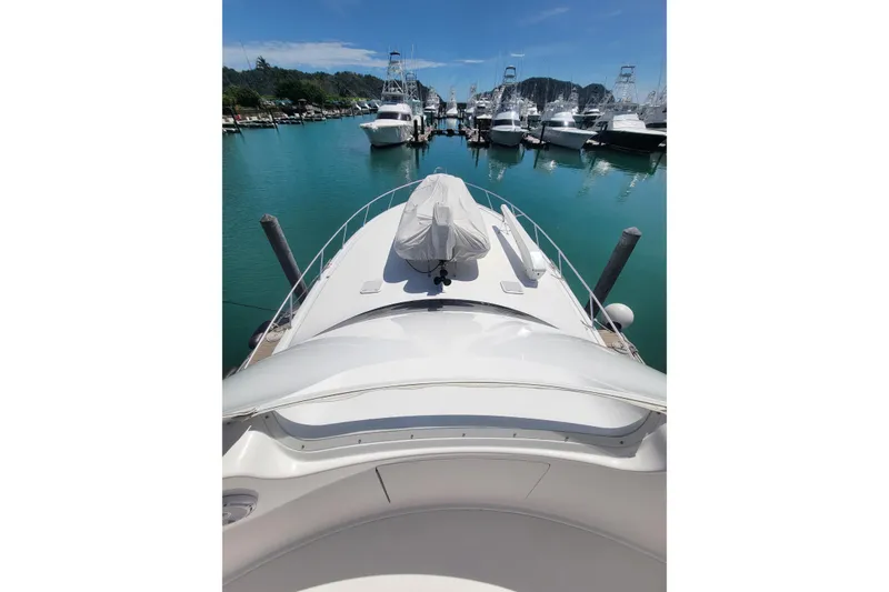 Slide: The Image of 2012 Viking 64c yacht docked in a marina, surrounded by calm water and other boats. - 6