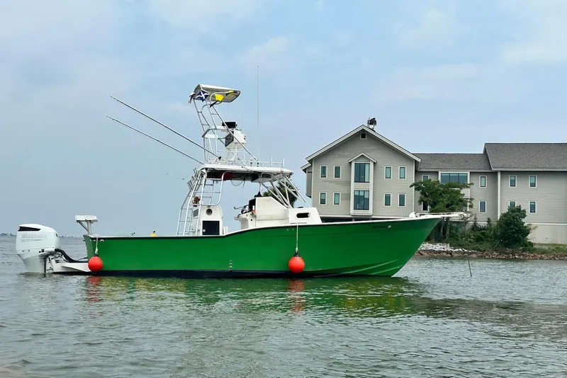 The Image of 2005 Mirage SF32 Center Console boat on water near a large house. - 0
