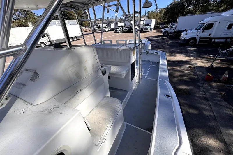 Slide: The Image of 2005 Mirage SF32 Center Console boat interior with seating and storage, parked near trucks. - 33