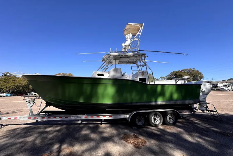 Slide: The Image of 2005 Mirage SF32 Center Console boat on trailer, green hull, clear blue sky background. - 4