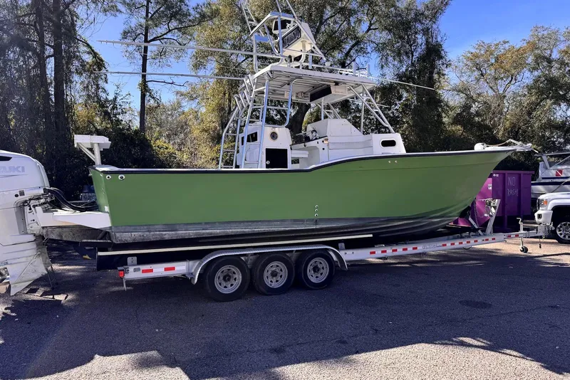 Slide: The Image of 2005 Mirage SF32 Center Console boat on trailer, green hull, parked outdoors. - 9