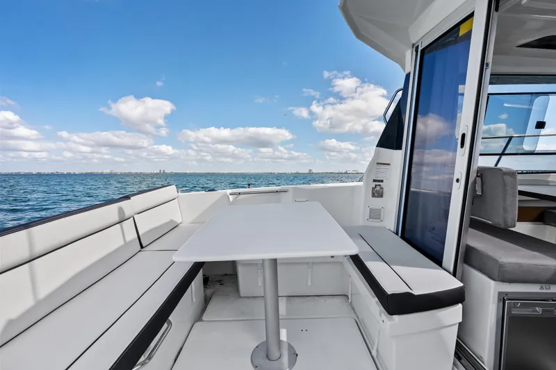 Slide: The Image of 2019 Jeanneau NC 795 boat with outdoor seating and table, overlooking the ocean. - 12