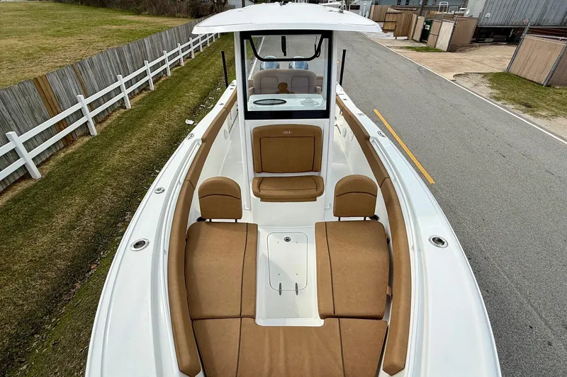 Slide: The Image of 2022 Sea Hunt Ultra 265 SE boat with tan seating, docked on a paved road. - 16