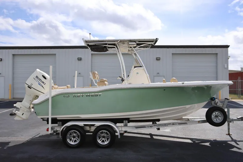 The Image of 2015 Key West 219 FS boat on trailer, parked outside industrial building. - 1