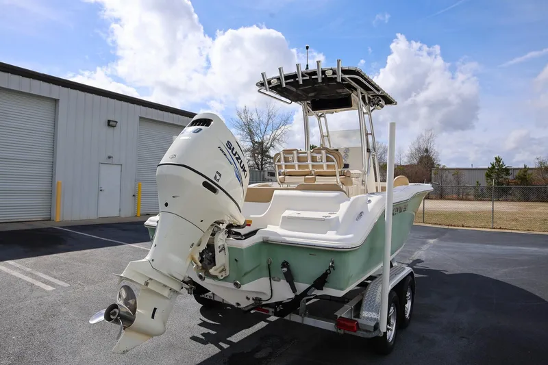 Slide: The Image of 2015 Key West 219 FS boat with Suzuki outboard motor on trailer, parked outdoors. - 2