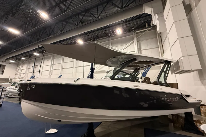 Slide: The Image of 2026 Monterey Elite 25 SD boat displayed indoors with canopy, sleek design. - 0