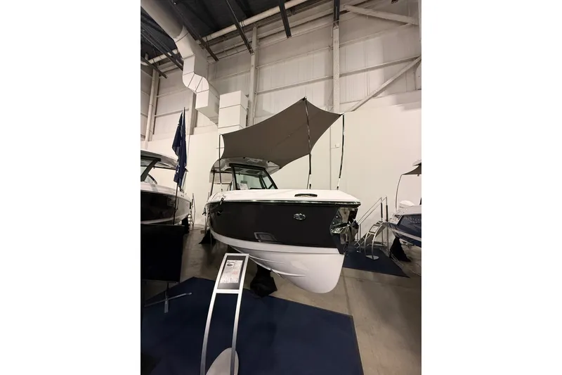 Slide: The Image of 2026 Monterey Elite 25 SD boat displayed indoors with canopy and sleek design. - 1