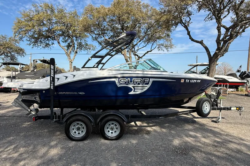 Slide: The Image of 2019 Chaparral 21 H2O Surf boat on trailer, parked outdoors under trees. - 2