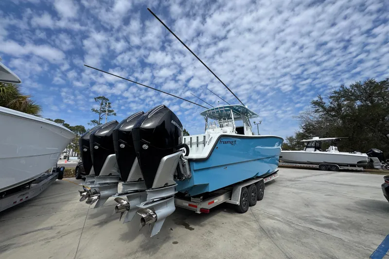 Slide: The Image of Blue 2016 Freeman 37VH boat with four engines on a trailer under a cloudy sky. - 13