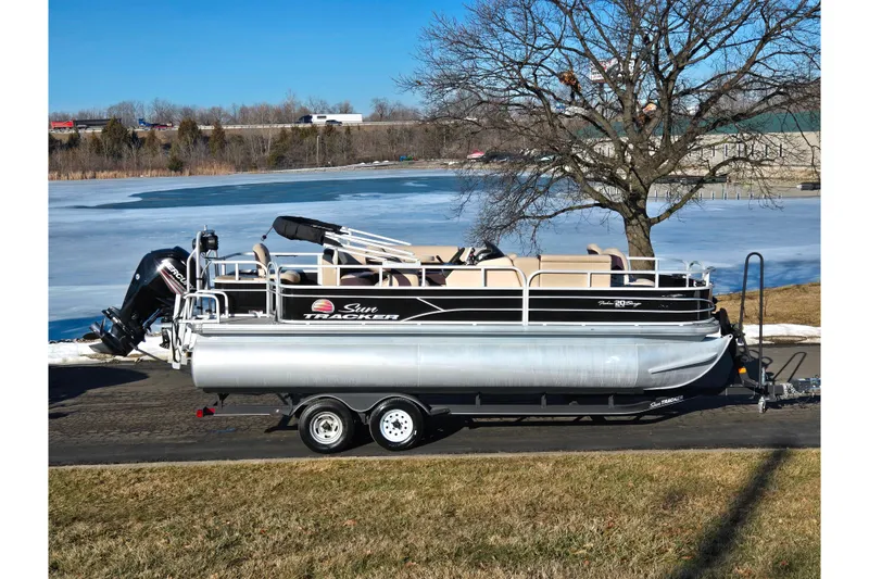 The Image of 2018 Sun Tracker Fishin' Barge 20 DLX pontoon boat on trailer by a frozen lake. - 0