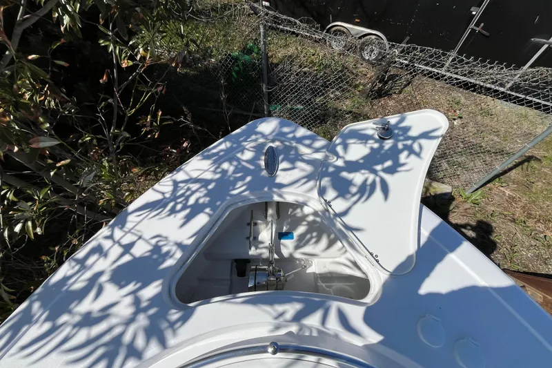 Slide: The Image of 2026 Sportsman Open 252 Center Console boat with open storage compartment, surrounded by foliage. - 14