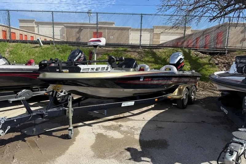 The Image of 2005 Bass Cat Puma boat on trailer, parked outdoors near storage units. - 1