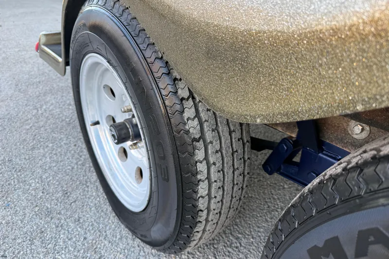 Slide: The Image of 2005 Bass Cat Puma trailer tire on asphalt, showcasing tread and wheel detail. - 28