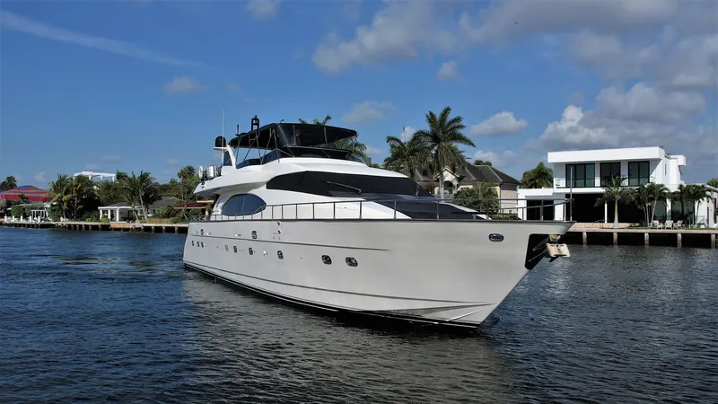 Slide: The Image of 1999 Azimut 85 Ultimate yacht cruising on a sunny day near waterfront homes. - 2