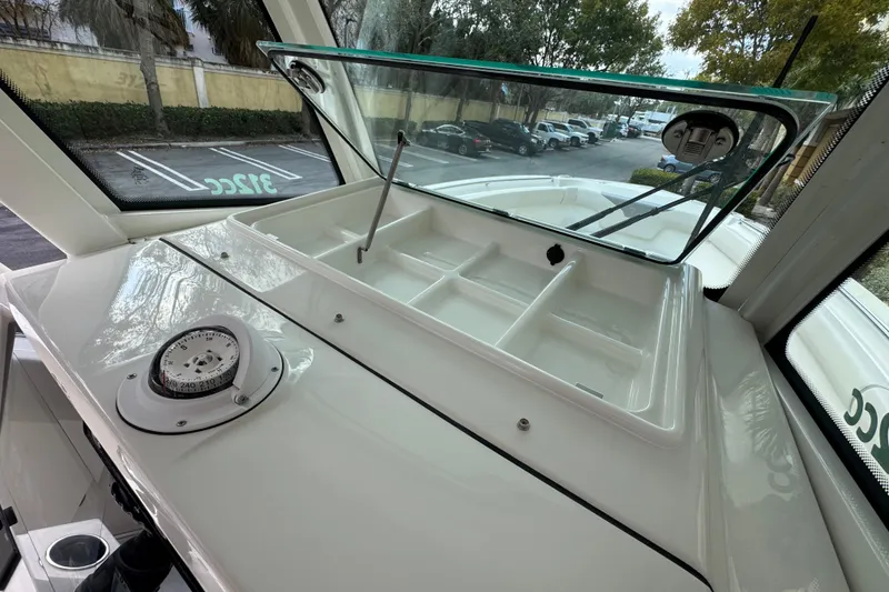 Slide: The Image of 2026 Sailfish 312 CC boat dashboard with compass and open storage compartment. - 27