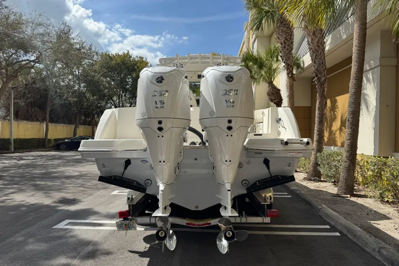 Slide: The Image of 2026 Sailfish 312 CC boat with dual outboard engines in a sunny parking lot. - 4