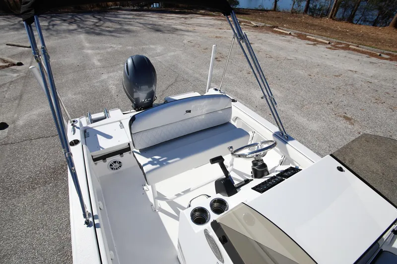 Slide: The Image of 2025 Stingray 173 CC boat interior with steering wheel and seating, parked on pavement. - 27