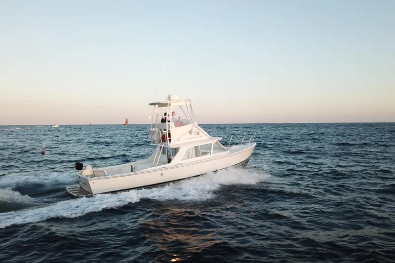 Slide: The Image of 1973 Bertram 31 Flybridge Cruiser navigating ocean waters at sunset. - 12