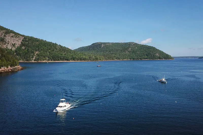 Slide: The Image of 1973 Bertram 31 Flybridge Cruiser on scenic lake with forested hills. - 15