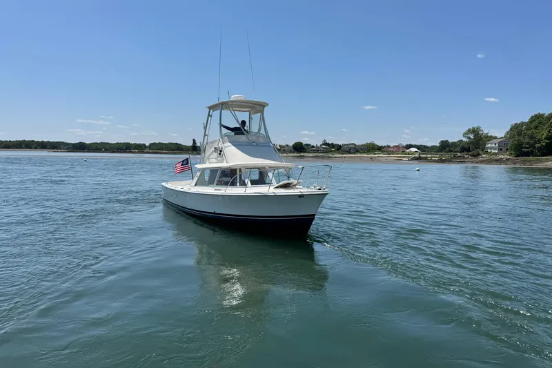 Slide: The Image of 1973 Bertram 31 Flybridge Cruiser on calm water, American flag, clear sky. - 17