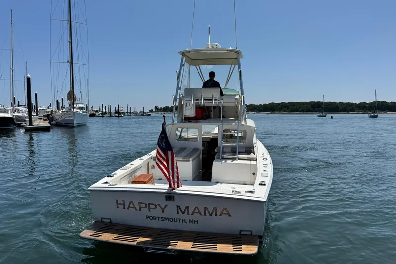 Slide: The Image of 1973 Bertram 31 Flybridge Cruiser "Happy Mama" in Portsmouth harbor, clear sky, American flag. - 24