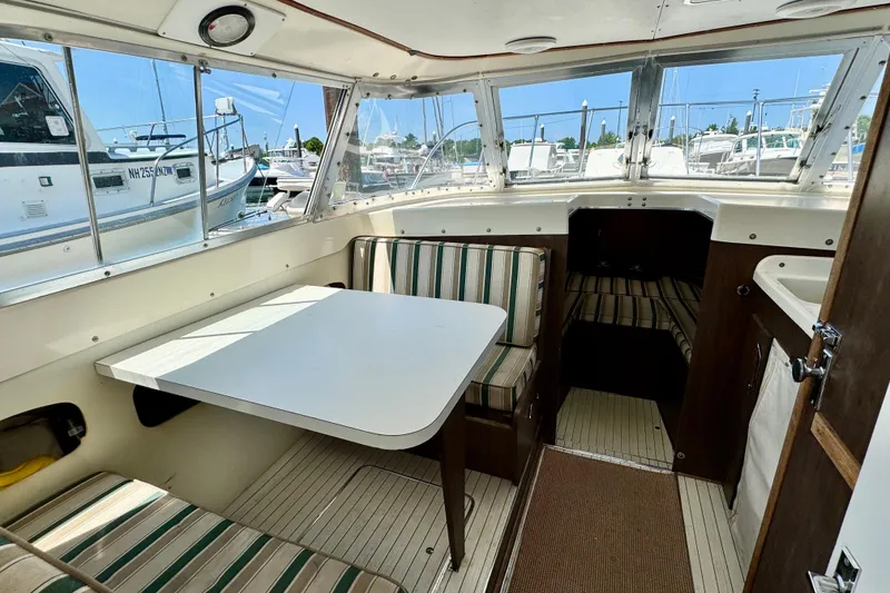 Slide: The Image of 1973 Bertram 31 Flybridge Cruiser interior with striped seating and table, docked at marina. - 4