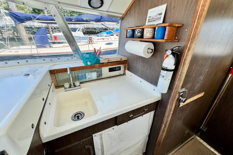 Slide: The Image of 1973 Bertram 31 Flybridge Cruiser interior with sink, storage, and window view of marina. - 7