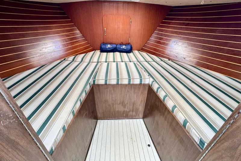 Slide: The Image of 1973 Bertram 31 Flybridge Cruiser cabin with striped cushions and wooden interior. - 8