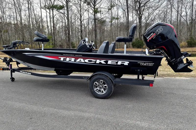 Slide: The Image of 2026 Tracker Pro Team 190 boat on trailer, parked on road with forest background. - 2