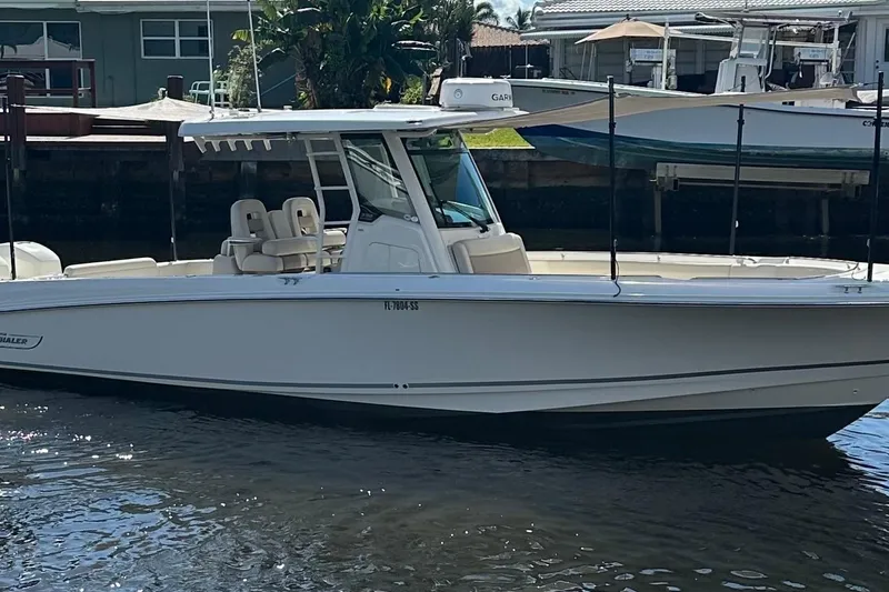 Slide: The Image of 2020 Boston Whaler 330 Outrage boat docked near waterfront homes. - 0