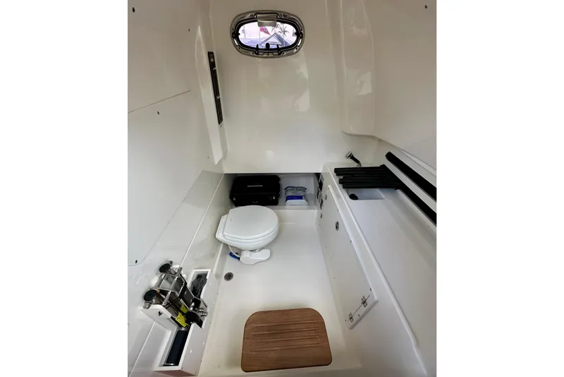 Slide: The Image of 2020 Boston Whaler 330 Outrage cabin interior with toilet and storage compartments. - 17
